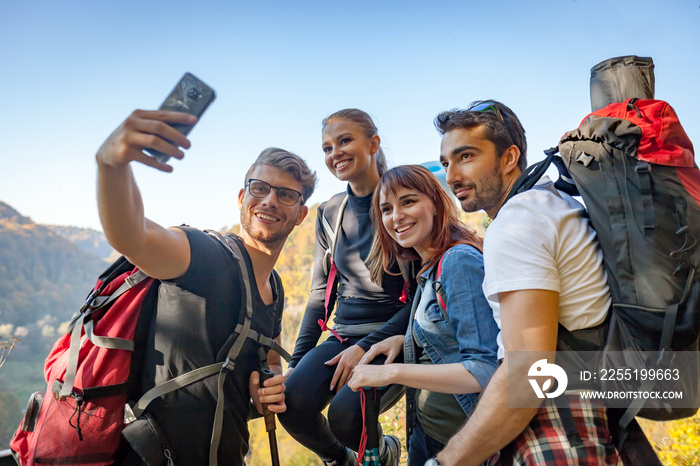 Friends with backpacks making selfie photo together at the peak of mount, travel and tourism concept