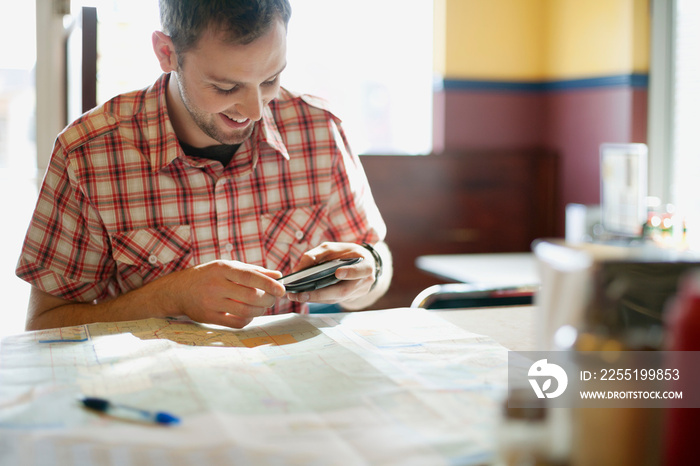 man using cell phone and map to plan trip