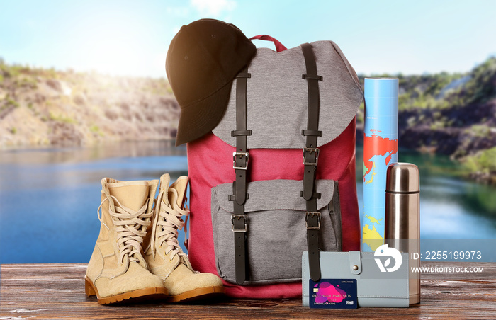 Set of traveler’s accessories on table near mountain lake