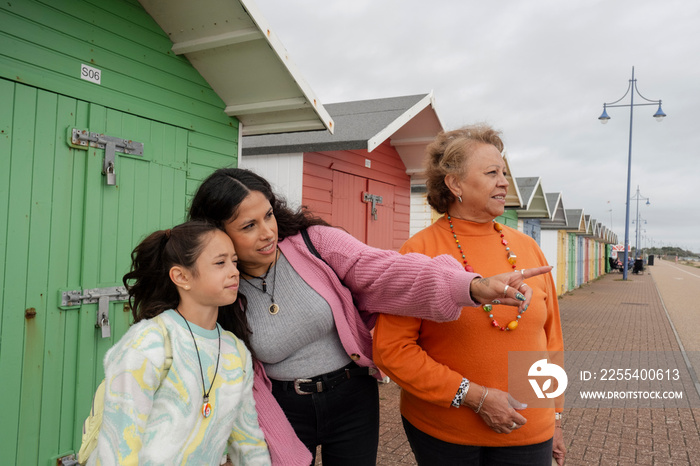 Grandmother, mother and granddaughter standing by beach hut