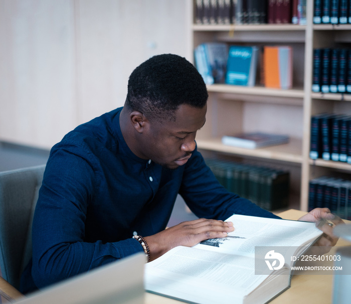 Young man reading book in public library