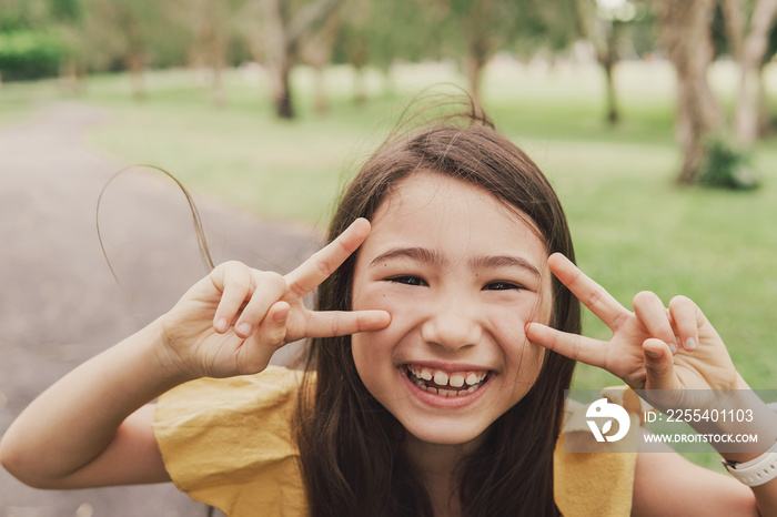 Close up urban lifestyle portrait of a confident, charming and gorgeous mixed race child face, happy multicultural Asian girl in park