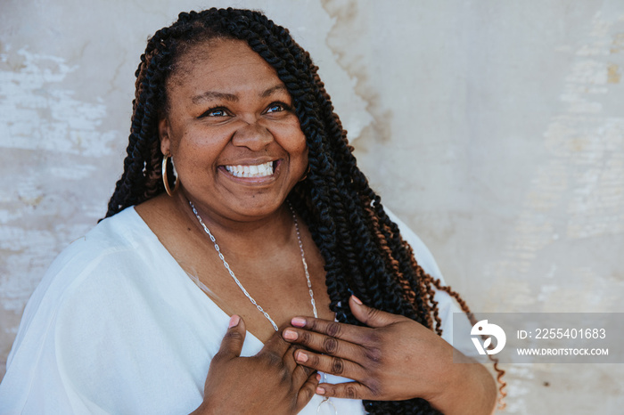 portrait of a plus size afro latinx haitian american woman with hands on heart looking up