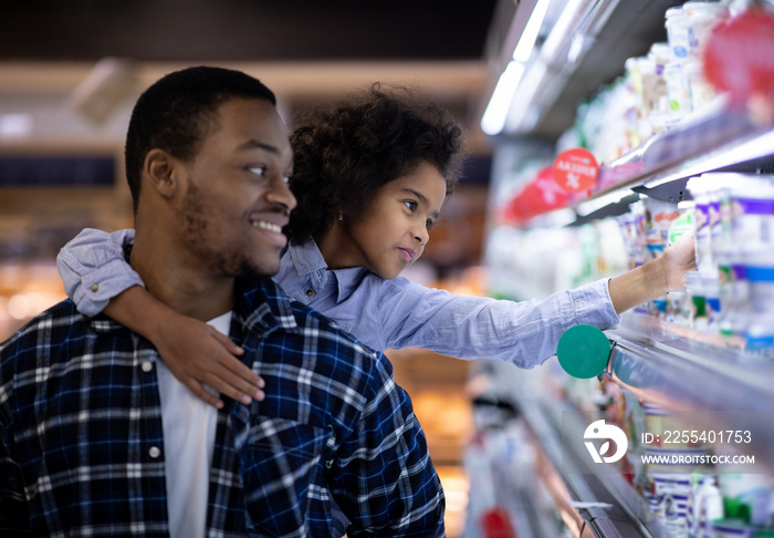 Happy black father with his cute daughter shopping for dairy products at big mall