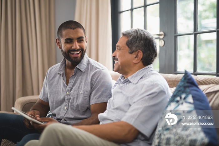 Happy man with his father sitting on couch at home