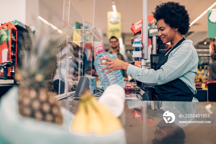 Beautiful smiling African American cashier working at a grocery store.