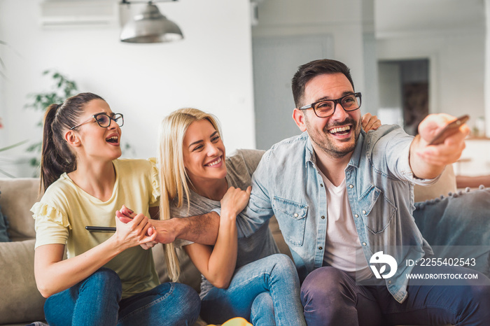 Three friends relax and watch television in bright living room