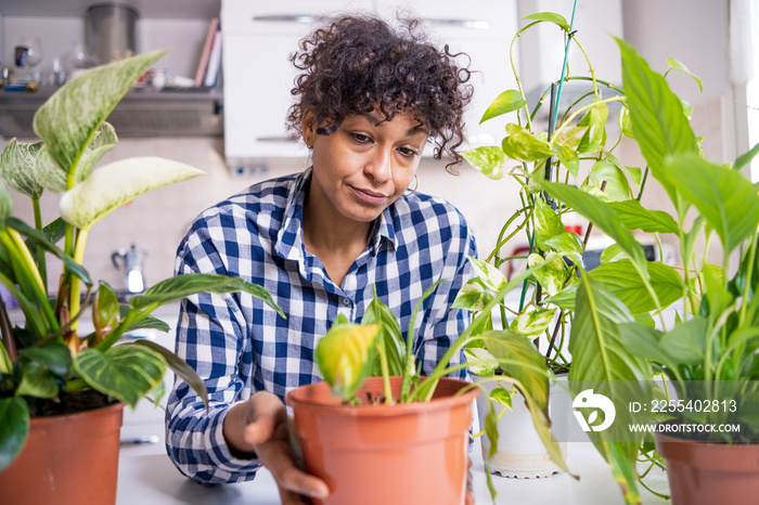 Black woman failing taking care of home plants feeling sad