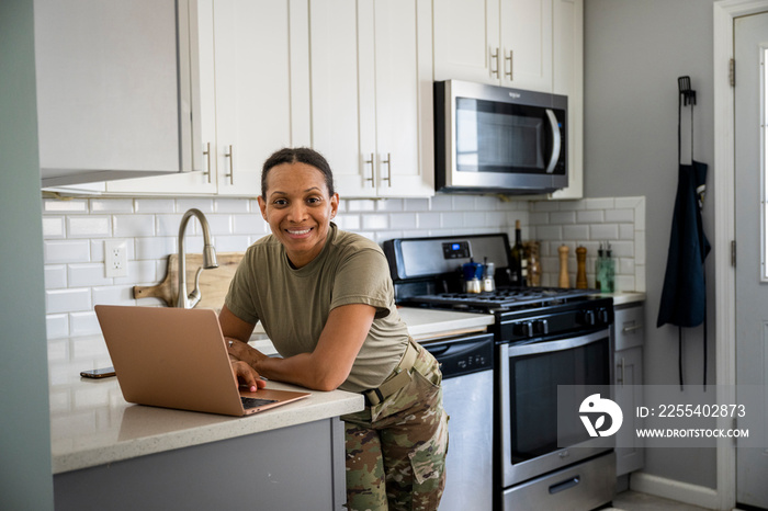 U.S. Army female soldier on her computer in her kitchen