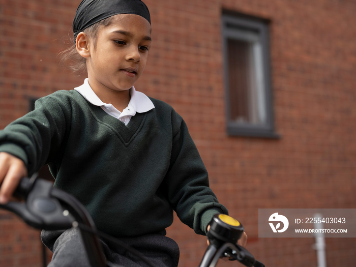 Boy (6-7) in school uniform riding bicycle