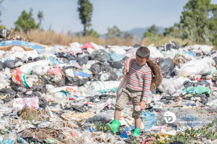 A poor boy collecting garbage waste from a landfill site in the outskirts .  children work at these sites to earn their livelihood. Poverty concept.