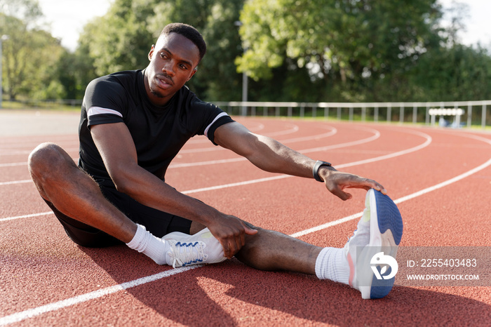 Athlete stretching legs before training at sports track