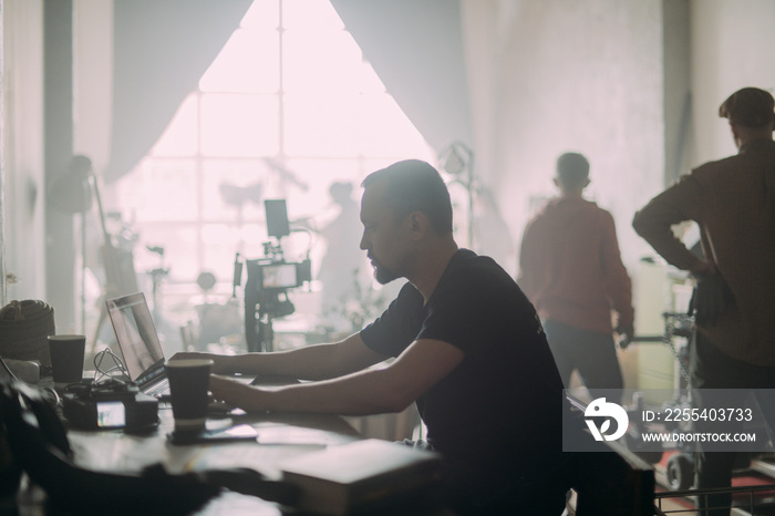 Editing director behind monitors on the set. A video editor edits video online while filming for a playback.