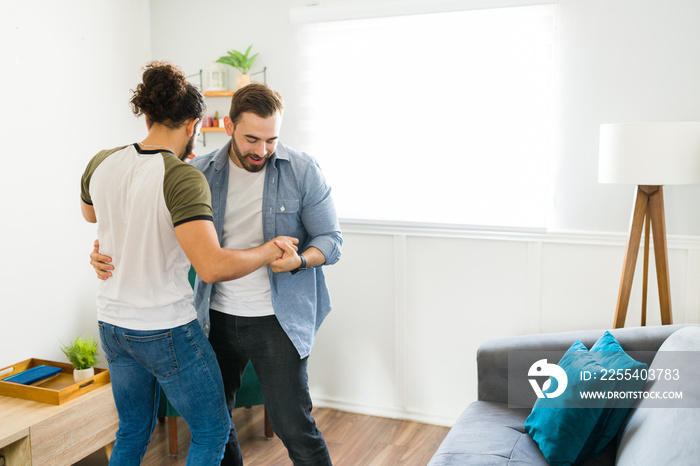 Gay caucasian man teaching his boyfriend how to dance