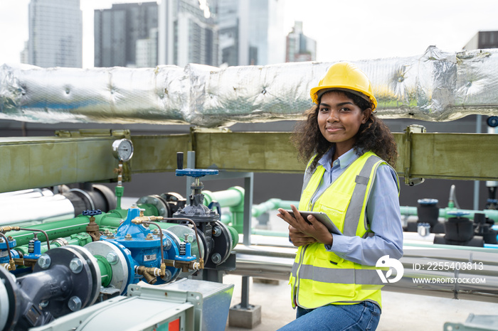 Worker woman or Industry maintenance engineer female dark skin wearing uniform and safety helmet under inspection and checking process on construction site.Industry,civil Engineer,construction concept