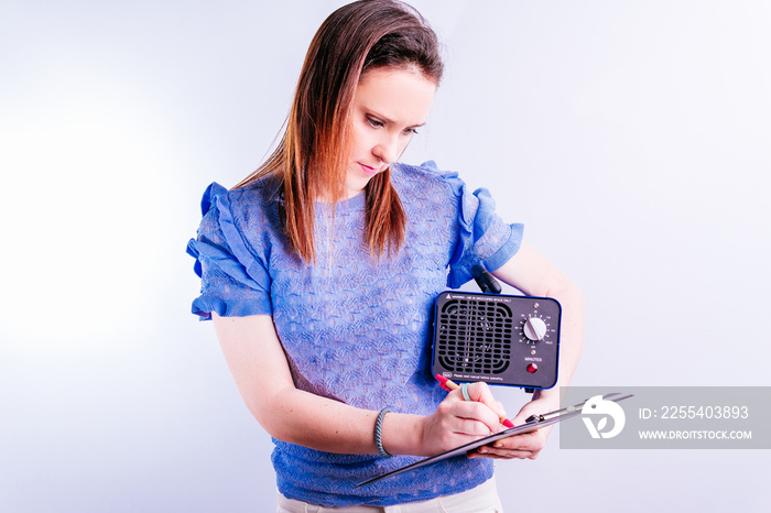 Young beautiful woman in charge of cleaning company holding an ozone generating machine writing orders . disinfection concept on white background. covid 19. professional industrial equipment