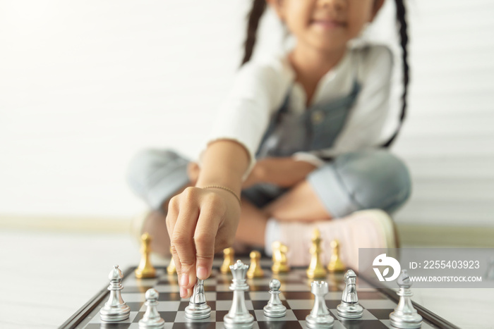 Happy asian girl playing chess at home.