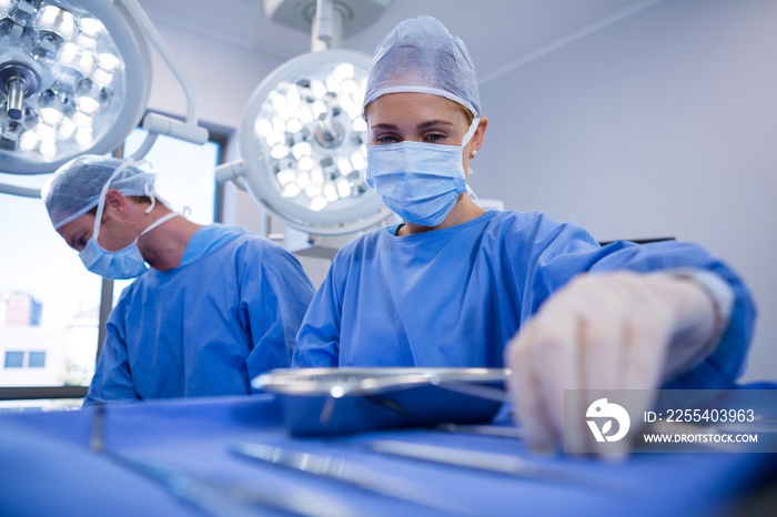 Female surgeon selecting surgical tools in operation theater