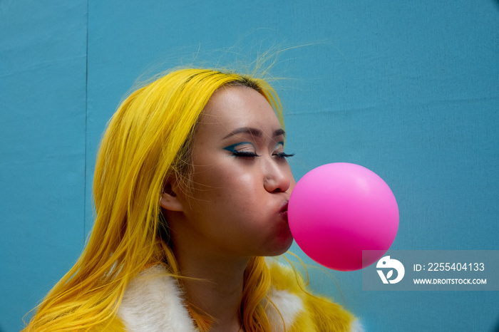 Young woman with yellow hair blowing bubble gum
