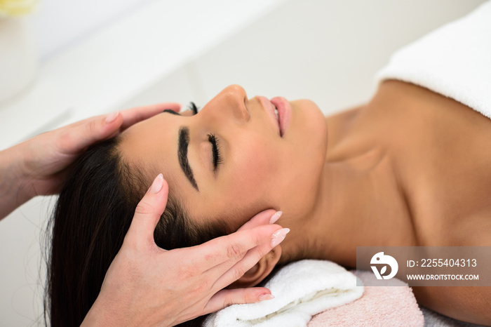 Woman receiving head massage in spa wellness center.