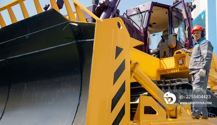 Industrial driver of yellow bulldozer gets into coal loading cab in open pit mine