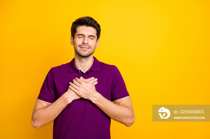 Portrait of his he nice attractive peaceful kind grateful guy wearing lilac shirt touching heart closed eyes isolated over bright vivid shine vibrant yellow color background