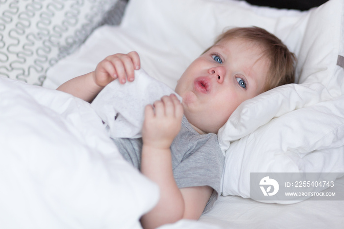 Little kid boy with sore throat cough in the bed close-up