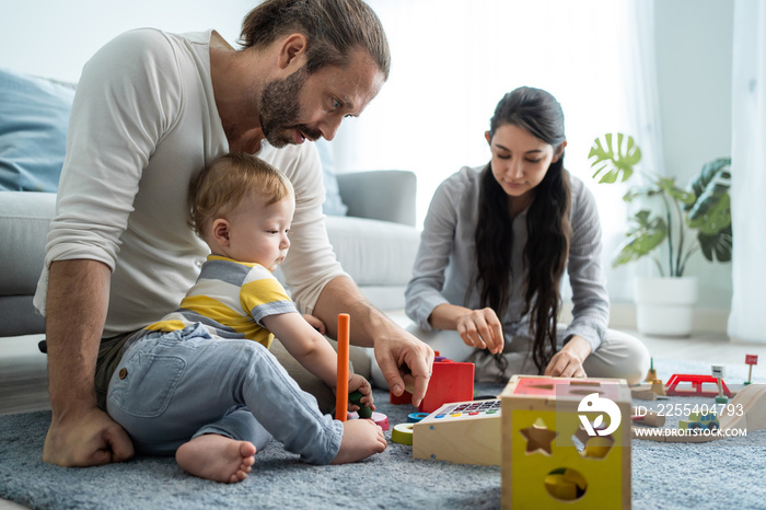 Caucasian happy loving parent play with baby toddler in living room.