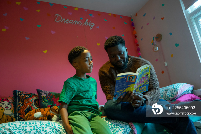 Father reading to son (6-7) in bedroom