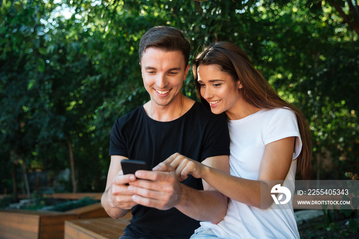 Portrait of a joyful young couple looking at mobile phone