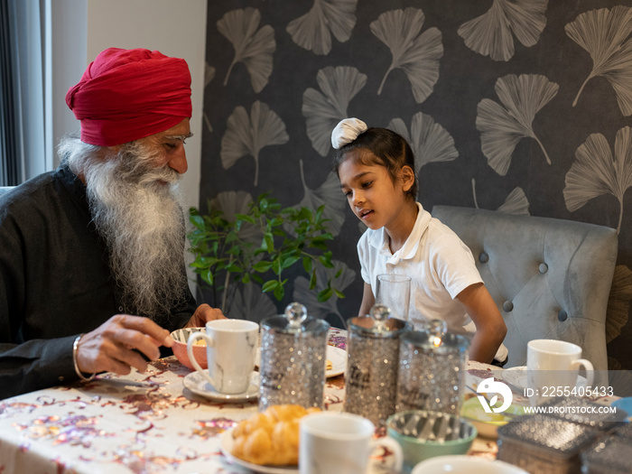 Grandfather and grandson (6-7) having afternoon tea at home