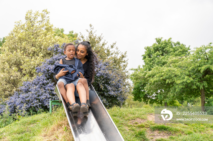 Mother and son having fun on slide at playground