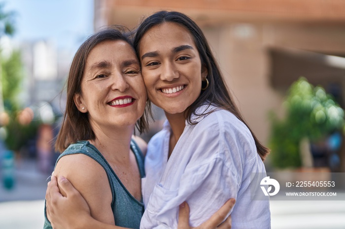 Two women mother and daughter smiling confident hugging each other at street