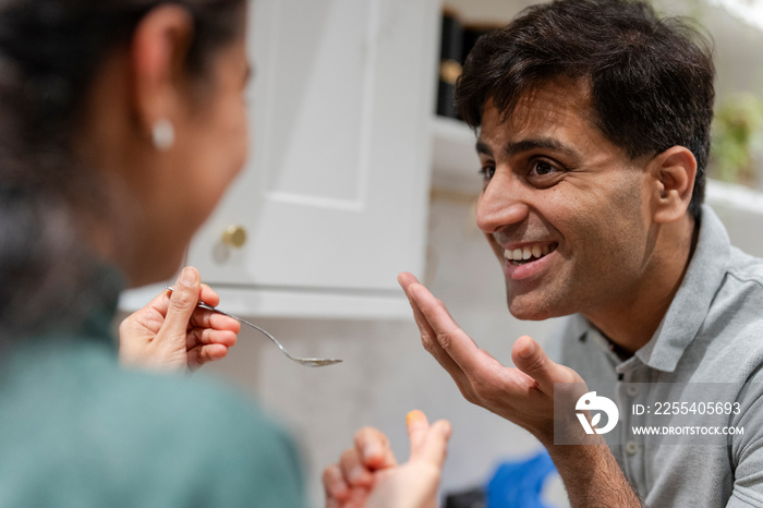 Woman giving husband dish to taste