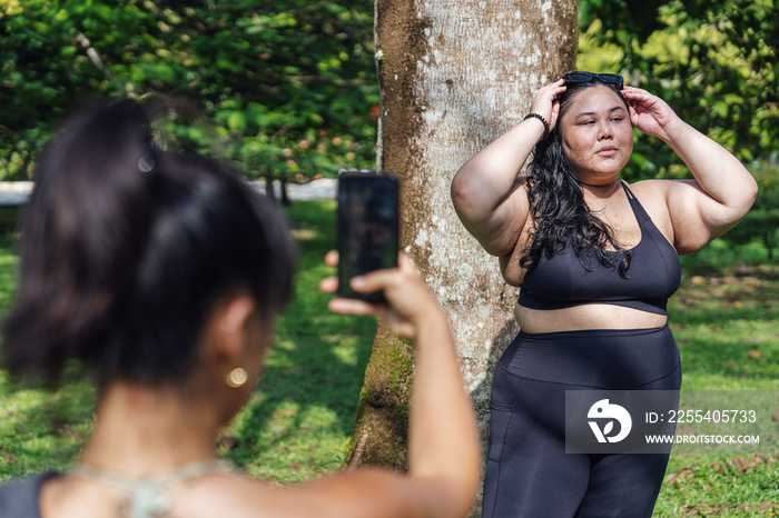 Friends taking photos of each other in the park after a workout