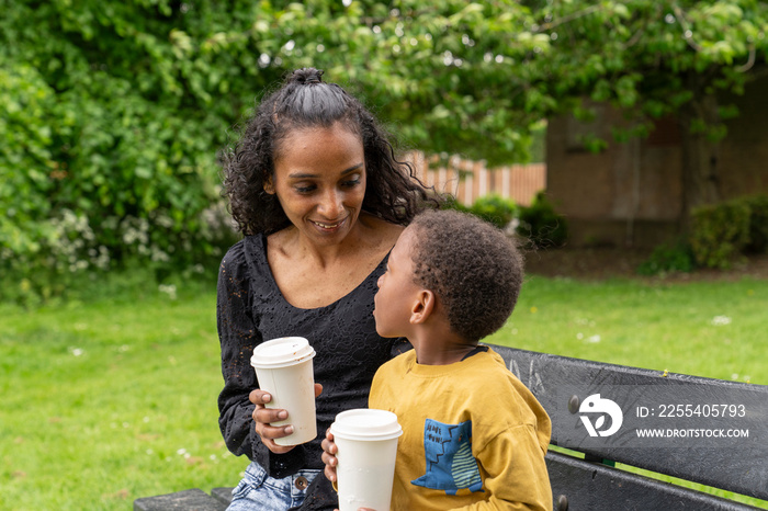 Mother and son sitting on bench in park