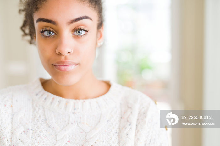 Beautiful young african american woman with afro hair wearing casual sweater Relaxed with serious expression on face. Simple and natural with crossed arms