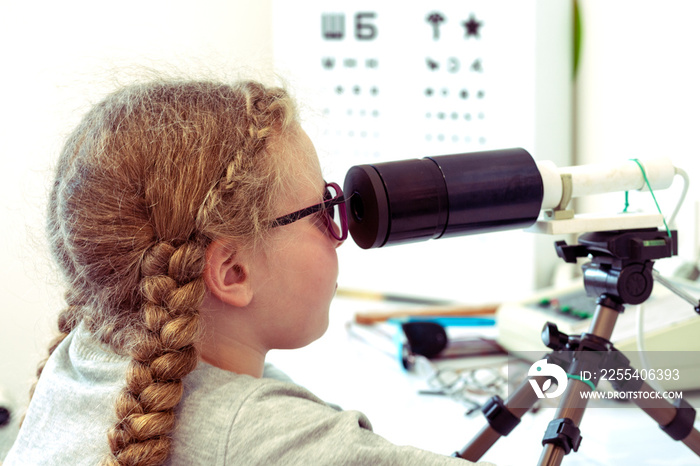 A girl is sitting in front of a device for stimulating vision.Ophthalmic equipment. Orthoptic and Pleoptic Therapy.Concept of recovery and training of vision. The concept of vision treatment children.