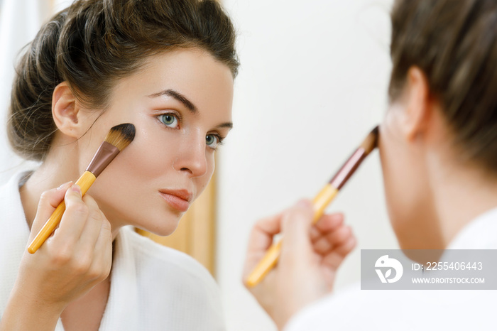 Woman applying foundation or blusher on her face