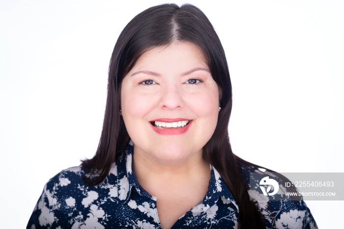 Headshot closeup of a beautiful latin lady. She is standing facing the camera over white background while she is smiling