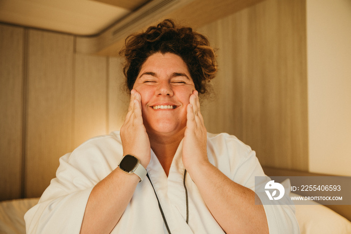 woman massages cheeks while smiling eyes closed