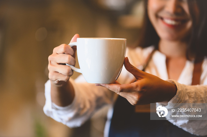 Closeup of white coffee cup with beautiful Asian woman barista background for serving to customer. Job and occupation. Food and drink beverage. Coffee shop and Cafe. Business and restaurant ownership