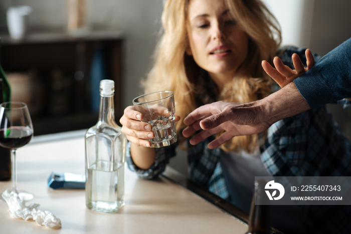 Close up of male hand while taking away glass with alcohol