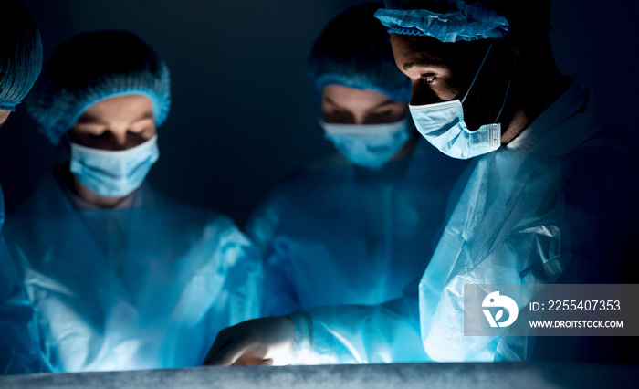 Surgeons performing surgical operation in dark operating room