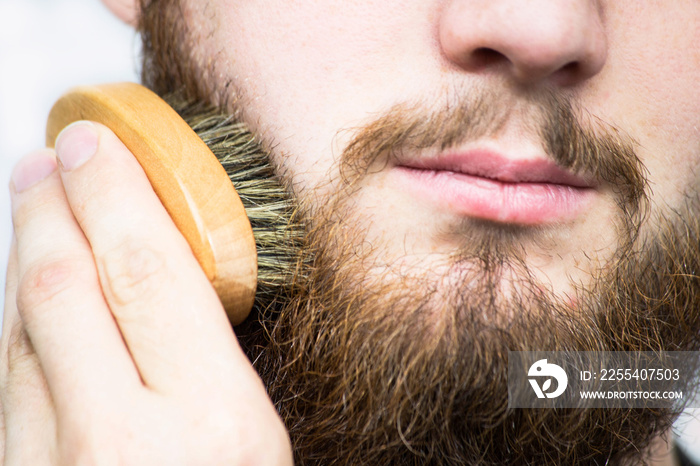 Hand of barber brushing beard. Barbershop customer,front view. Beard grooming tips for beginners.