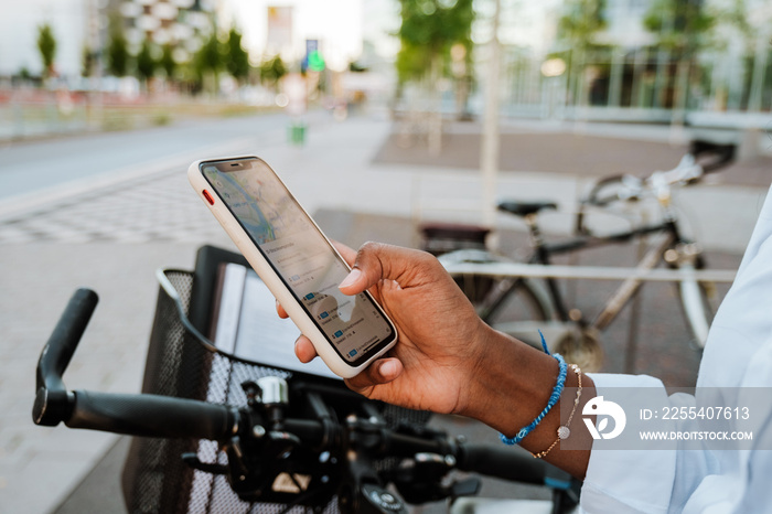 Young indian woman using cellphone while riding bicycle on city street