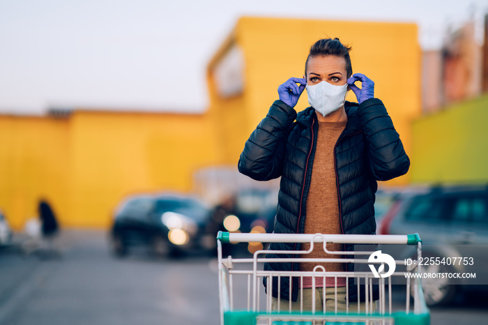 A woman wears medical protective gloves and a mask while shopping groceries.