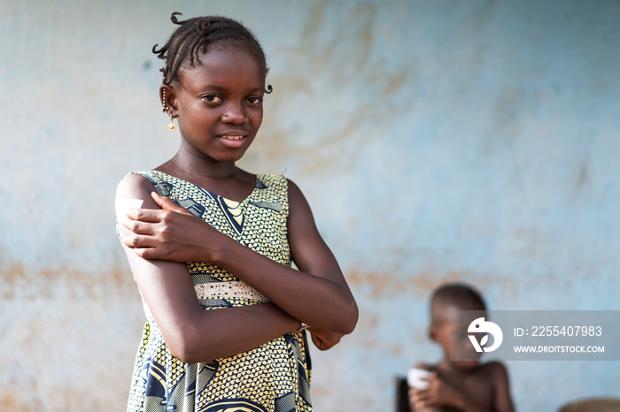 Relieved beautiful little black girl pressing her fingers firmly on the injection site covered by a large plaster after participating in a school vaccination program in rural Africa