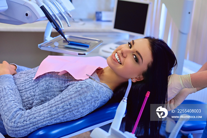 Attractive brunette female on a dentist chair in a stomatology room.