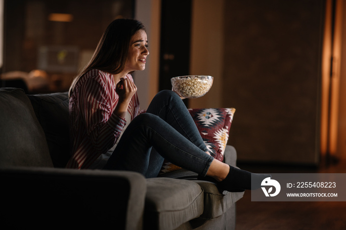 Young woman at home. Beautiful woman sitting in living room watching movie.